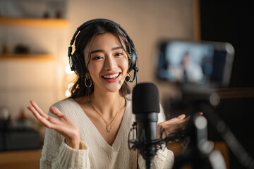 Smiling female podcaster in a cozy home studio, wearing headset and speaking into a microphone while live-streaming content on camera