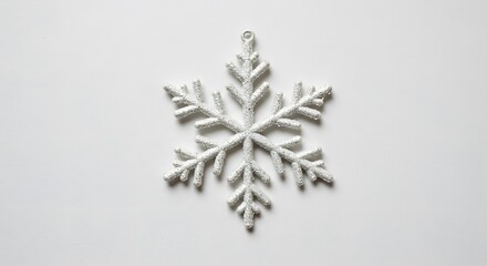 A sparkling white snowflake ornament on a white background. A winter holiday season decoration.