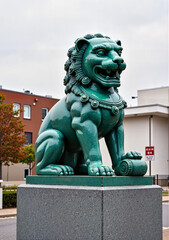 Green lion statue on pedestal in urban environment for Lunar New Year  
