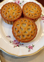 Three traditional Lunar New Year mooncakes on decorative plate  