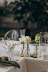 Elegant Table Setting with Delicate Flowers and Citrus Accents for a Refined Dining Experience in a Well-Lit Indoor Space Surrounded by Lush Greenery