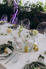 Elegant Dining Table Arrangement Featuring Candles, Fresh Flowers, and Lemon Accents for a Special Event in a Lush Greenery Setting