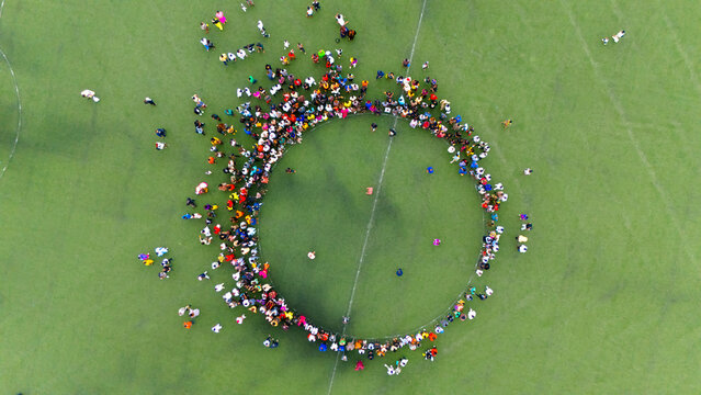 Port Harcourt, Nigeria - 28 September 2025: Aerial view of a vibrant circle of people standing on a lush green field, their colorful clothing contrasting with the verdant expanse.