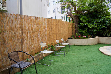 A Serene Outdoor Space Featuring Metal and Fabric Chairs Set Against a Lush Green Garden Landscape With Bamboo Fencing