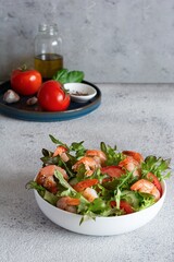 Fresh crispy salad with vegetables and shrimps in a white plate on a light background. Healthy food concept.