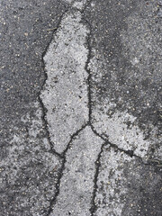 Weathered asphalt texture with large cracks forming a bright grey abstract pattern