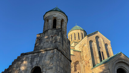 The majestic Bagrati Cathedral in Kutaisi, Georgia, stands proudly against a clear blue sky. This ancient UNESCO World Heritage Site showcases impressive Georgian architecture and history.