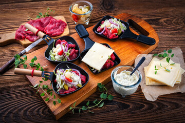 Traditional authentic Swiss raclette with beef meat, pickles, savoy cheese and spicy yogurt topping...