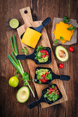 Vegetarian raclette with mached avocado, lime and cheddar cheese served as top view on a wooden...