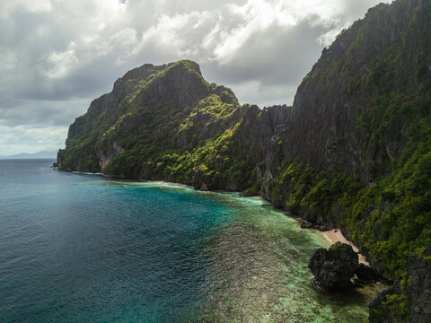 Aerial of beach tucked between awe-inspiring rocks on the Philippines 