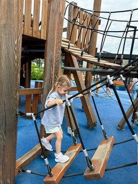 Child crossing rope bridge at wooden playground