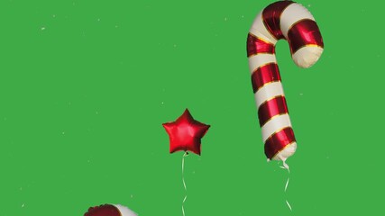falling Christmas snow andfoil balloons in the shape of Christmas candies move from bottom to top on a green screen - Powered by Adobe