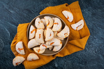 italian sweet ravioli cookies with apricote jam filling served as top view on a black board