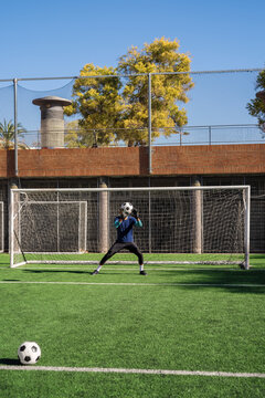 Goalkeeper training shot stopping at soccer goal