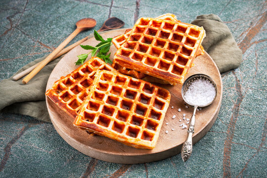 Fresh baked homemade Brussels waffles with pearl sugar served as close-up on a wooden board