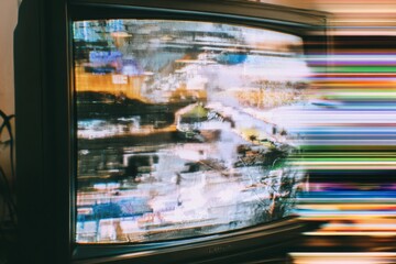 An old television screen displays colorful vertical lines and strong horizontal light streaks indicating a severe signal disruption.