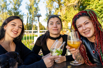 Diverse friends making a funny face while raising a toast with cocktails outdoors