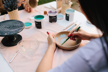 Ceramic bowl decorated with blue paint designs shows detailed process of pottery painting of handmade ceramics. Ceramic bowl with painted blue designs inside. Blue paint drawings inside ceramic bowl.