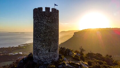 Ancient stone tower at sunrise, overlooking a bay