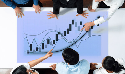 A diverse group of business professionals collaborating over financial charts and graphs, analyzing stock market trends and making strategic decisions in a modern office space. Axiom