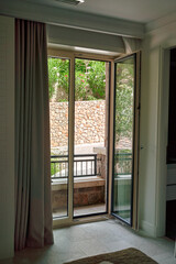 Elegant Open French Doors Leading to a Serene Outdoor Space Surrounded by Lush Greenery and Rustic Stone Walls
