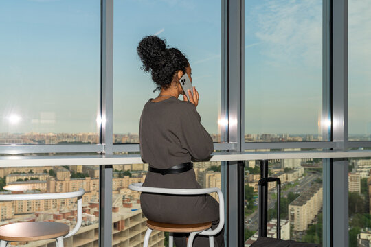 Businesswoman on Phone in Hotel Lobby Overlooking City Skyline
