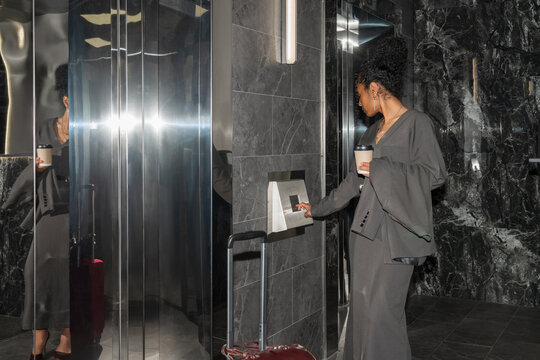 Businesswoman Using Keypad to Call Hotel Lift