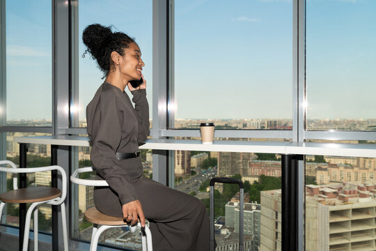 Businesswoman Talking on Phone in Hotel Lobby with City View