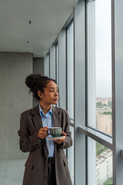 Businesswoman Holding Coffee Cup by Hotel Window