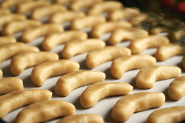 Closeup of raw sweet pastry on a baking sheet - preparation of vanilla crescents or Kipferl, traditional Christmas cookies