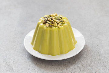 Pistachio cream pudding. On a plate. Light gray background