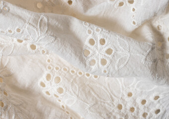 Obraz premium close-up of a white cotton fabric with delicate floral embroidery and cutwork details, material with soft texture and elegant handcrafted appearance