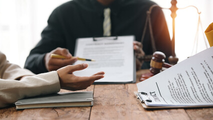 Lawyer discussing legal contract with client in office, providing advice and consultation. Scales of justice and gavel on desk