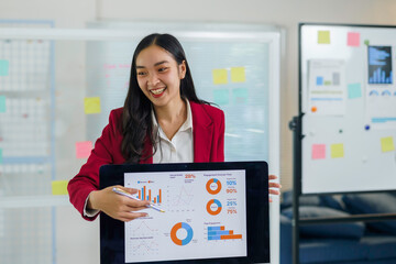 Asian businesswoman presenting marketing data and financial analytics, smiling and discussing business growth strategy in office meeting
