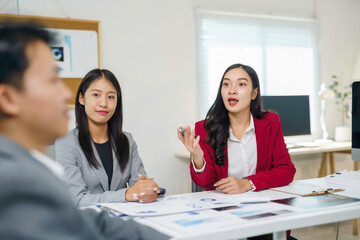 Asian business women presenting ideas during a corporate meeting, collaborating on market data and financial reports