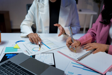 Business professionals collaborating on a project, analyzing financial data and charts, and documenting ideas during an office meeting