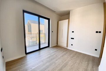 Bright and Spacious Modern Room with Large Windows Overlooking Outdoor Balcony, Offering Natural Light and Contemporary Design Elements for Relaxation