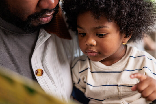 Father and child reading together, bonding over a book.