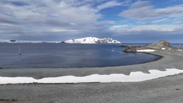 A red yacht is moored near the coast of Antarctica.