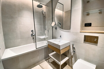 Modern Bathroom Design Featuring Glass Shower, Sleek Bathtub, Round Mirror, and Minimalist Fixtures for a Comfortable and Stylish Ambiance
