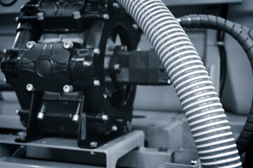 A hose is attached to a black machine. The hose is wrapped around the machine