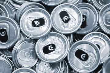 A pile of empty aluminum beer or beverage can lids. The lids are stacked haphazardly on top of each other and are all the same size.