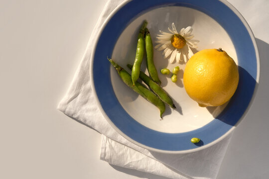 Fresh Lemon, Green Beans and Flower on white plate with a blue border.