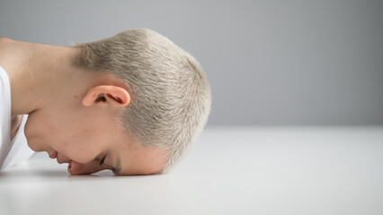 Fototapeta premium Sad woman sitting with her head on the table on a white background.