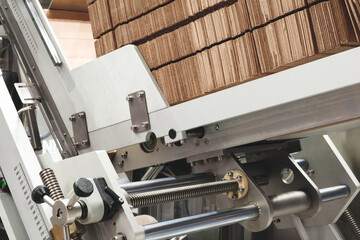 Folded cardboard boxes stand in a row on a packaging machine conveyor ready to be opened and filled with food products.