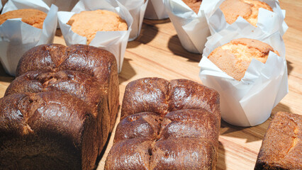 table with variety baked goods, including muffins, scones, and cakes. muffins are in paper cups, and cakes are in paper cups as well. table is set up for gathering or event.
