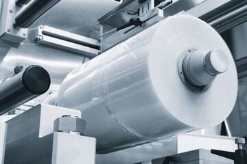 Automatic polyethylene plastic bag production machine with lighting effect. Close-up of the roller of plastic bag production machine in light blue scene. product packaging concept