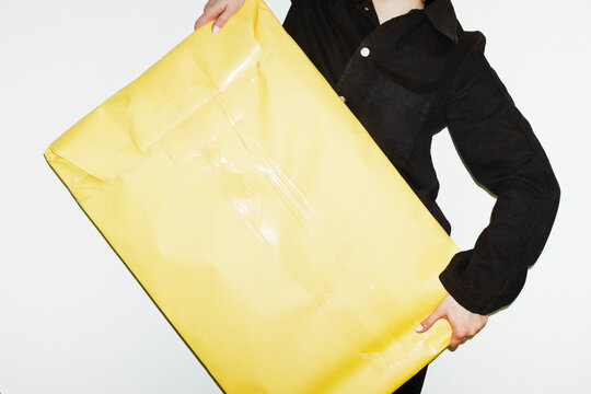 Person carrying huge yellow paper package with space place for text