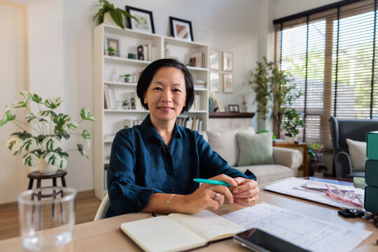 Woman at desk in home office, smiling at camera.