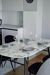 Elegant Dining Setup Featuring a Marble Table with Stylish Glassware and Contemporary Chairs in a Modern Kitchen Environment